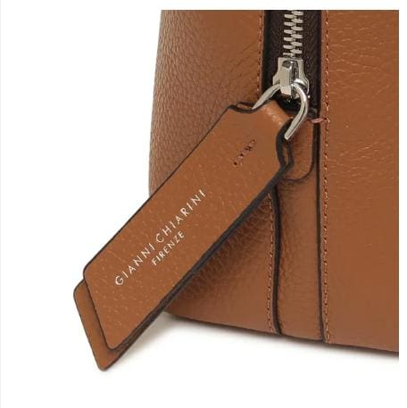 Primer plano del bolso de cuero marrón de GIANNI CHIARINI. Tiene una cremallera metálica y una etiqueta de cuero que dice "GIANNI CHIARINI FIRENZE" en blanco. Está hecho en Italia y emana una elegancia italiana atemporal.