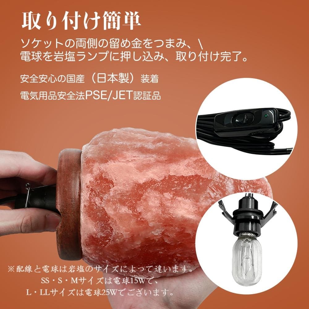 手が「天然岩塩ランプ【サイズ：SS】—ほっと落ち着く、やさしい間接照明」に電球を差し込み、お部屋の間接照明としてその穏やかな自然な輝きを際立たせています。 日本語の説明文には、ランプの安全機能、公式認証、および対応する電球サイズが記載されています。上部にはスイッチ付きの黒いコードが写っており、このヒマラヤ岩塩アクセサリーの利便性と実用性を際立たせています。.