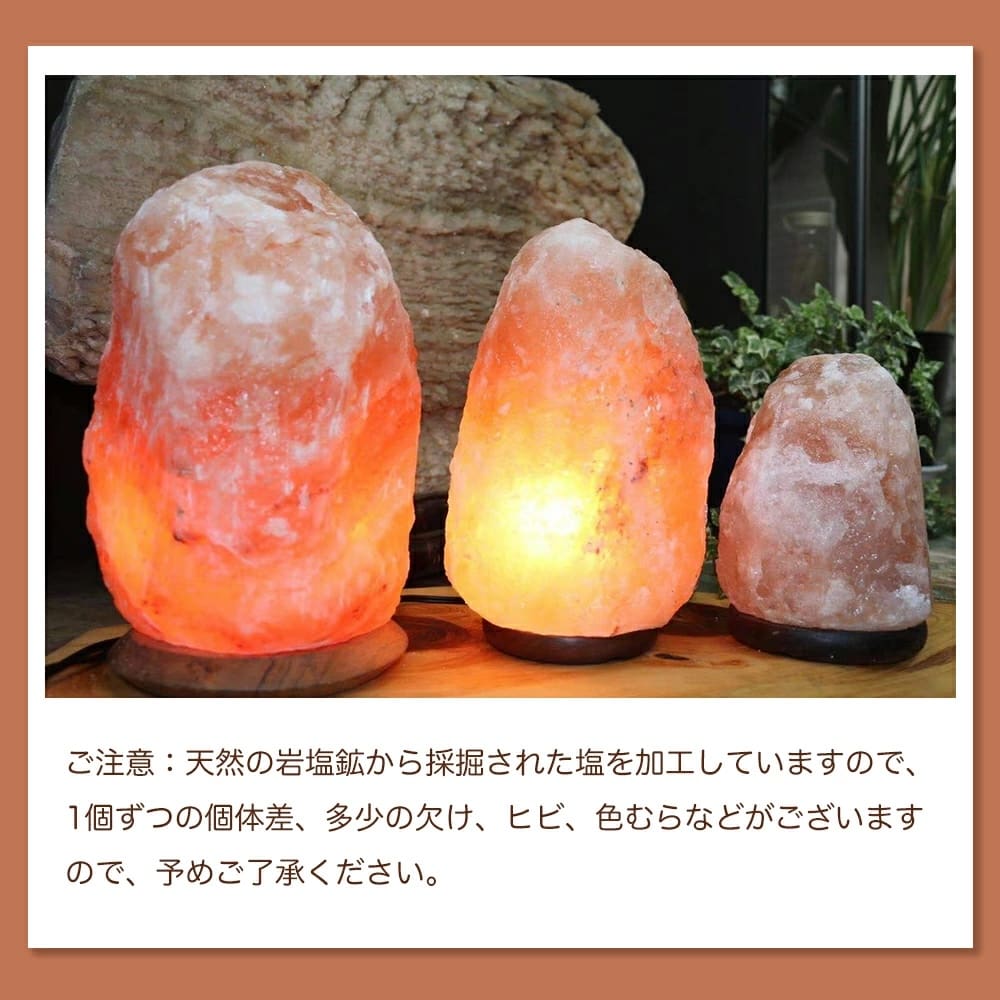 提供された製品データを反映して修正した文章は以下の通りです：3つの天然岩塩ランプ【サイズ：SS】—ほっと落ち着く、やさしい間接照明—が木製の台の上に置かれ、その優しい光で部屋を柔らかく照らし、エレガントな間接照明となっています。 以下の日本語の注記には、天然素材であるため、ランプごとに外観が自然に異なることが説明されています。.